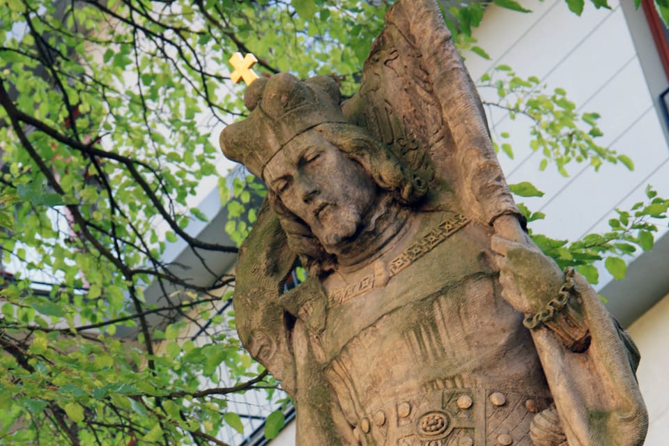El santo tiene una corona de príncipe, una larga capa y un estandarte en la mano izquierda. Con la mano derecha da su bendición. En el cinto cuelga su espada | Foto: Barbora Němcová, Radio Prague International El santo tiene una corona de príncipe, una larga capa y un estandarte en la mano izquierda. Con la mano derecha da su bendición. En el cinto cuelga su espada | Foto: Barbora Němcová, Radio Prague International